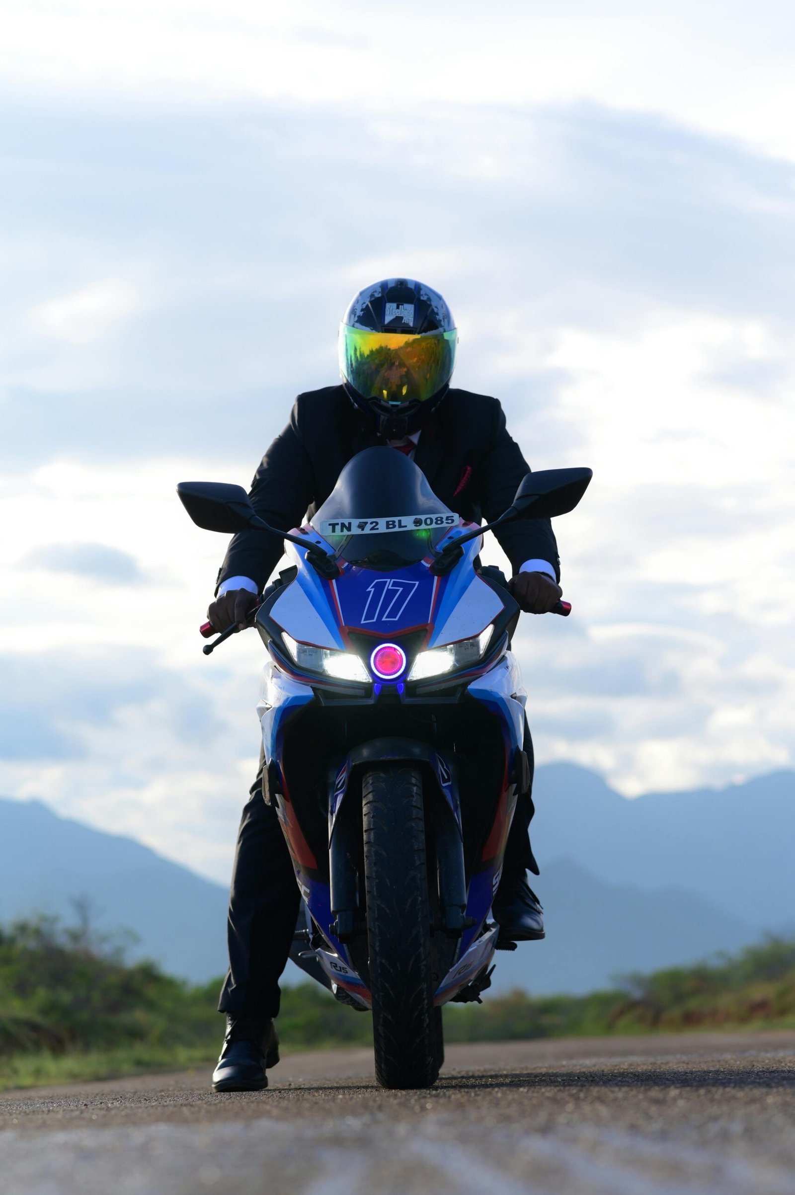 Motorcyclist in helmet rides Yamaha on open road with mountain backdrop.